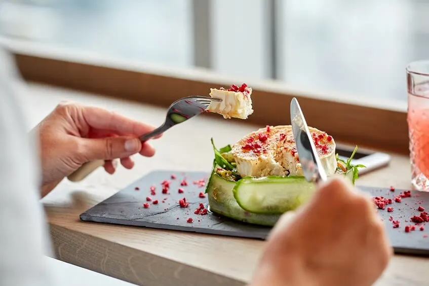 influencer eating a fancy plate of goat cheese salad at restaurant
