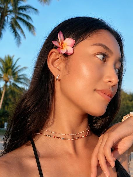 Creator on a beach, a flower tucked behind her ear